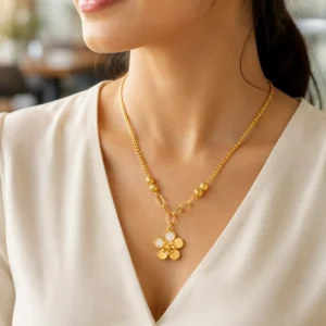 Woman wearing Elara Bloom anti-tarnish gold flower pendant necklace with textured bead accents and a white V-neck top