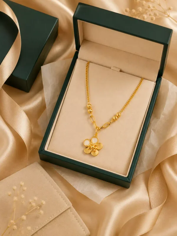 Gold flower pendant necklace displayed in a dark green jewellery box with champagne ribbon and neutral gift styling