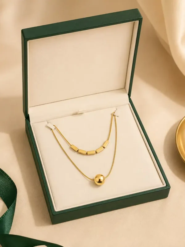 Aurevia Duo gold-tone layered necklace displayed in green jewellery presentation box