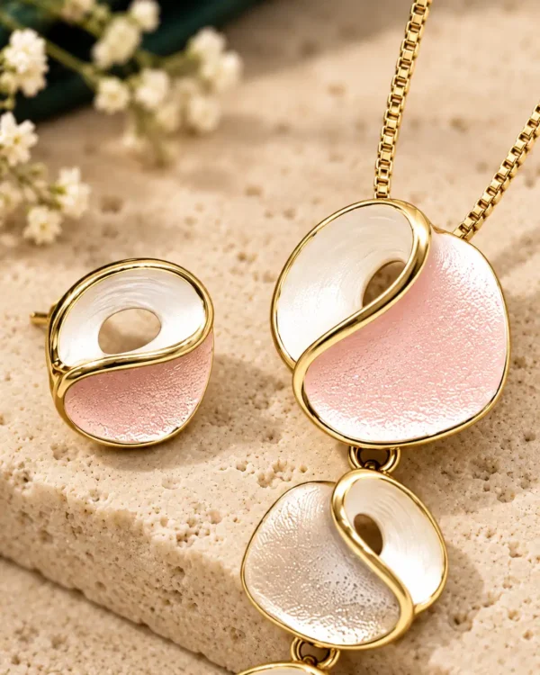 Close-up of Blush Orbit gold-tone pendant and stud showing textured blush pink and pearly white curved inlays