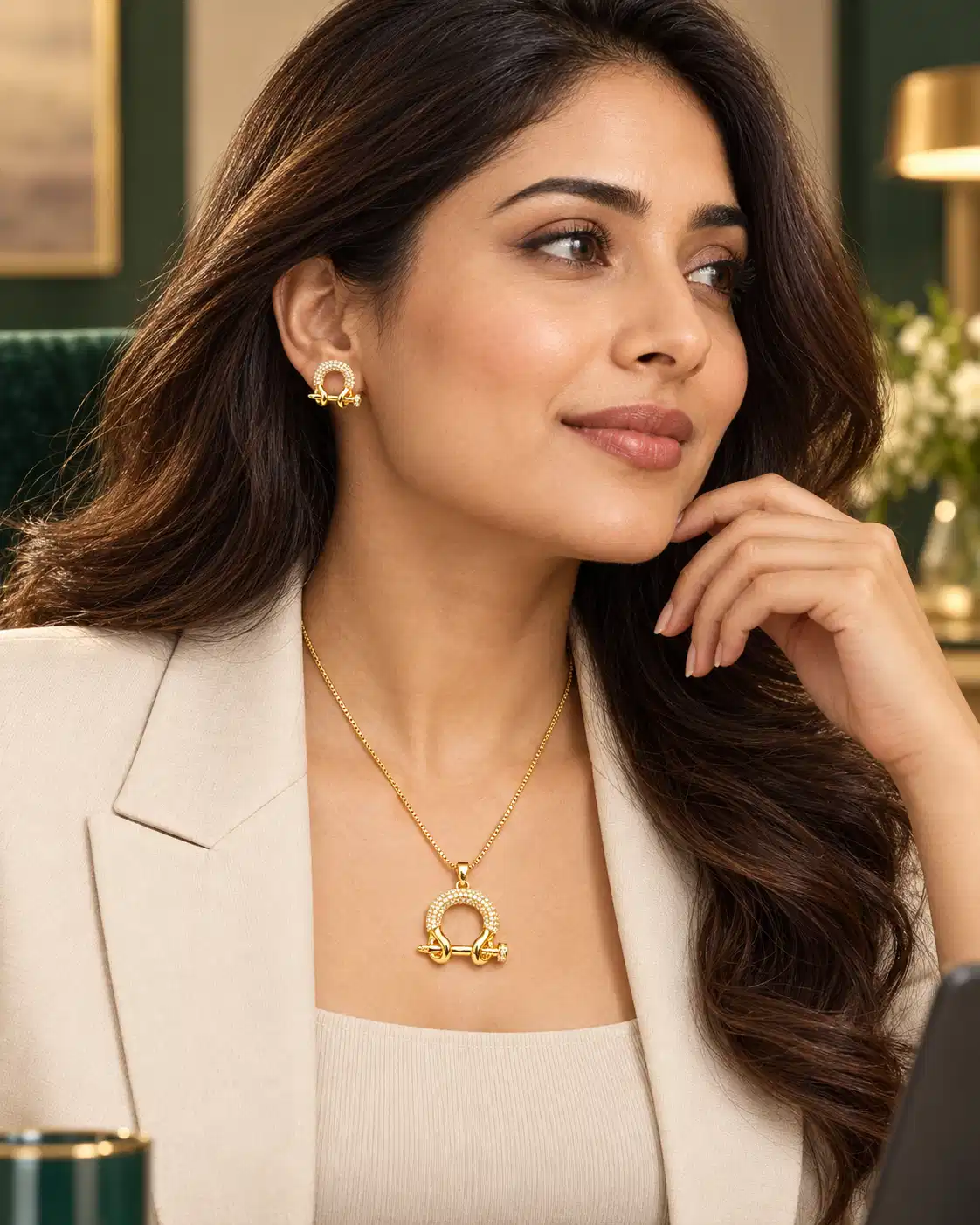 Woman in cream blazer wearing Aurelia gold crystal pendant necklace and matching stud earrings